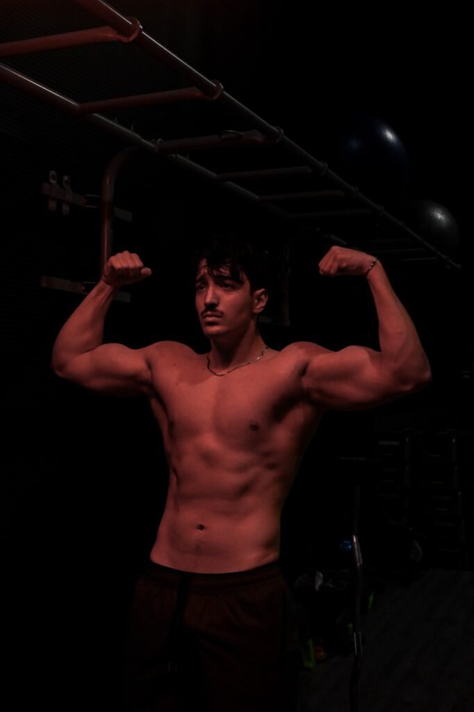 Pose double biceps en salle, éclairage latéral marqué