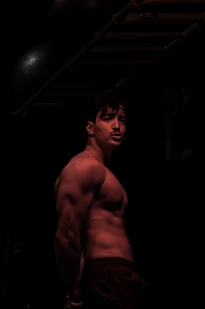Bodybuilder de profil, ombres nettes sur fond sombre